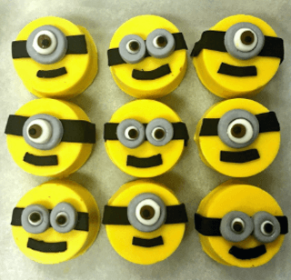 A bunch of cupcakes with minions faces on them