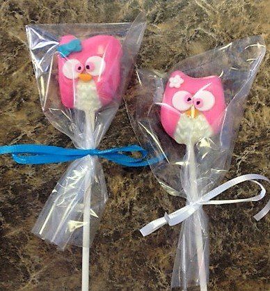 Two pink owl lollipops wrapped in plastic with a blue ribbon