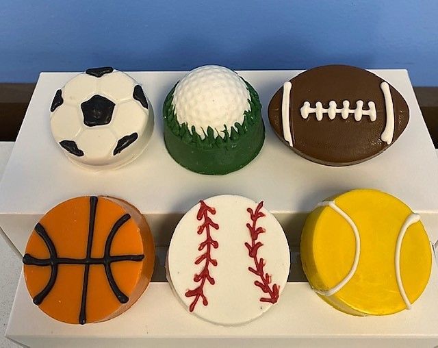Six cupcakes decorated to look like sports balls including a soccer ball a golf ball a basketball and a tennis ball