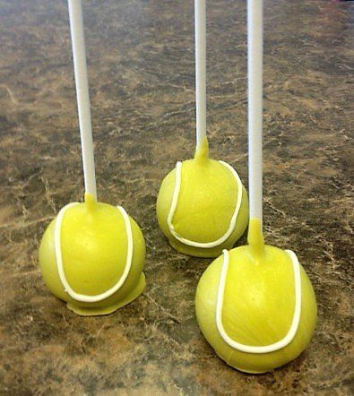 Three yellow tennis balls on sticks on a table