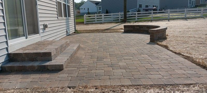 A patio with steps and a fire pit in front of a house.