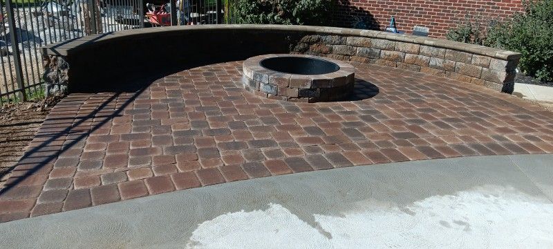 A fire pit is sitting in the middle of a brick patio.