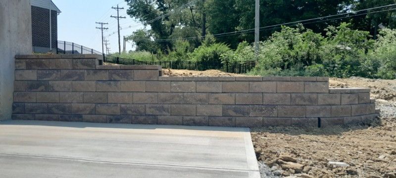 A brick wall is being built next to a concrete driveway.