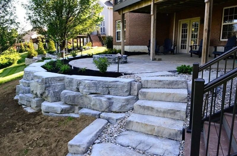 A stone walkway leading to a patio with a brick house in the background