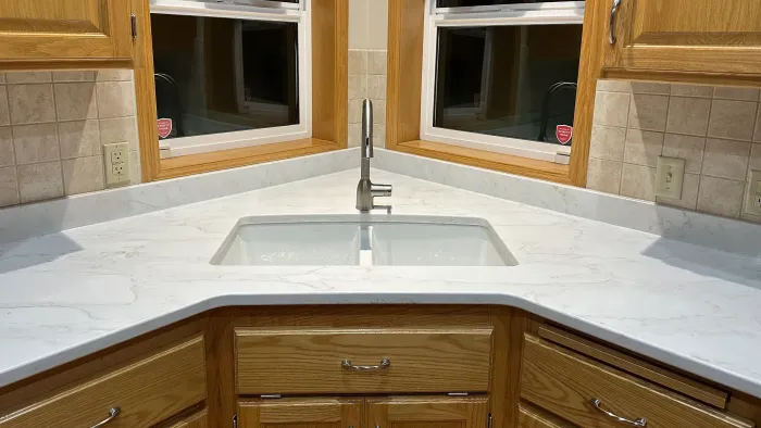 A kitchen with a sink and a window in the corner