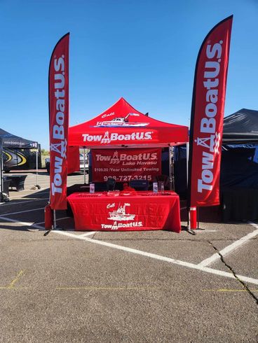 A Tow Boat US tent is sitting in a parking lot next to a table.