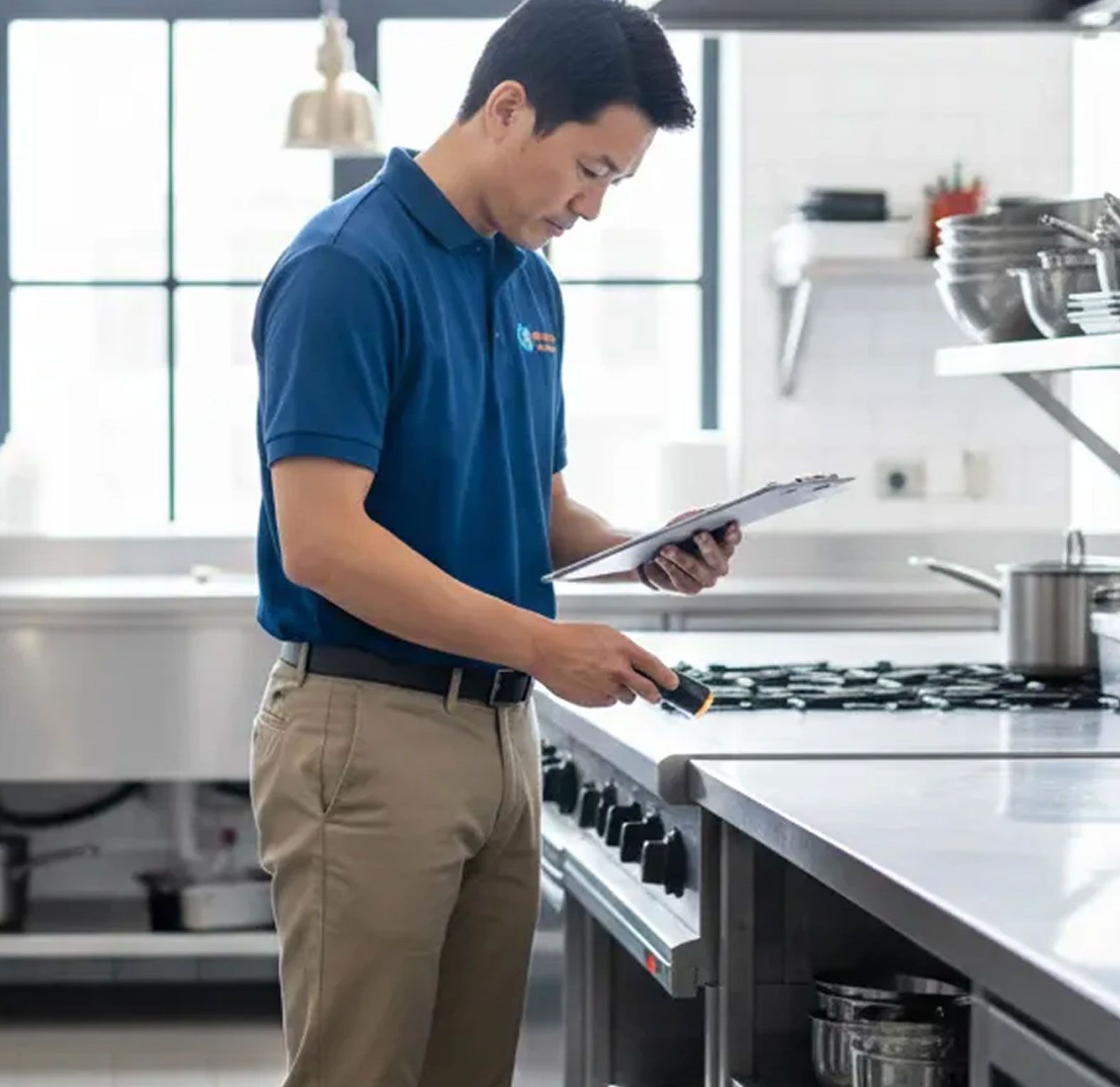 Technician inspecting a clipboard beside a kitchen stove in a bright, modern kitchen