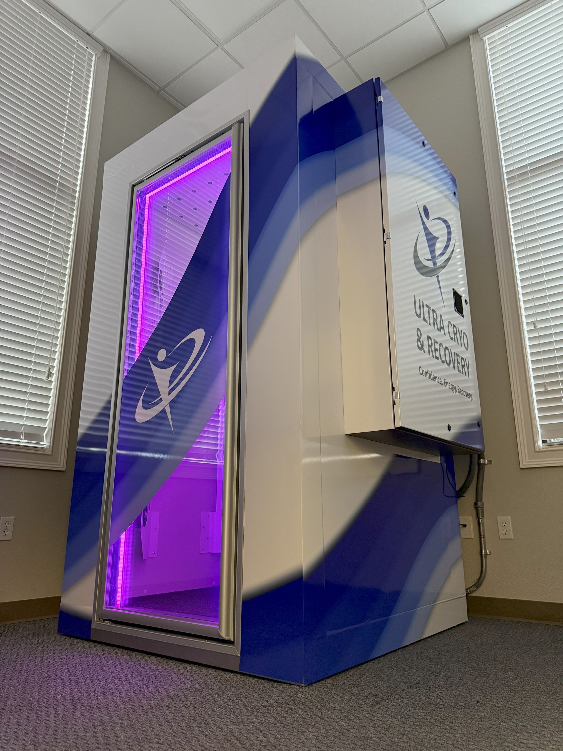 Cryotherapy chamber, blue and white with purple light, in a room with windows.