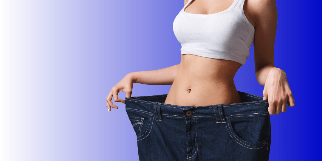 A woman in a white tank top holds open a pair of loose jeans, showcasing weight loss against a blue gradient background.