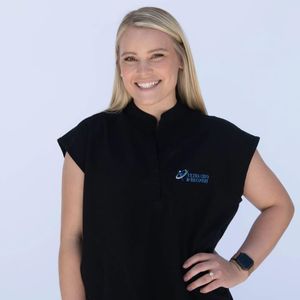 A woman wearing a black vest with a logo on it