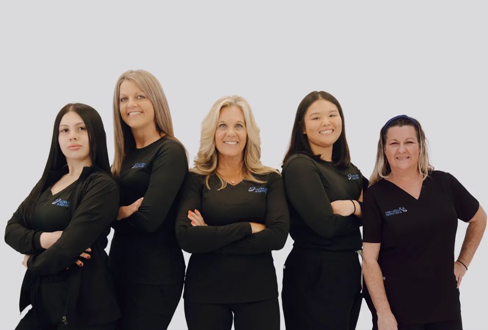 Five women in black shirts stand together with crossed arms, smiling in front of a white background.