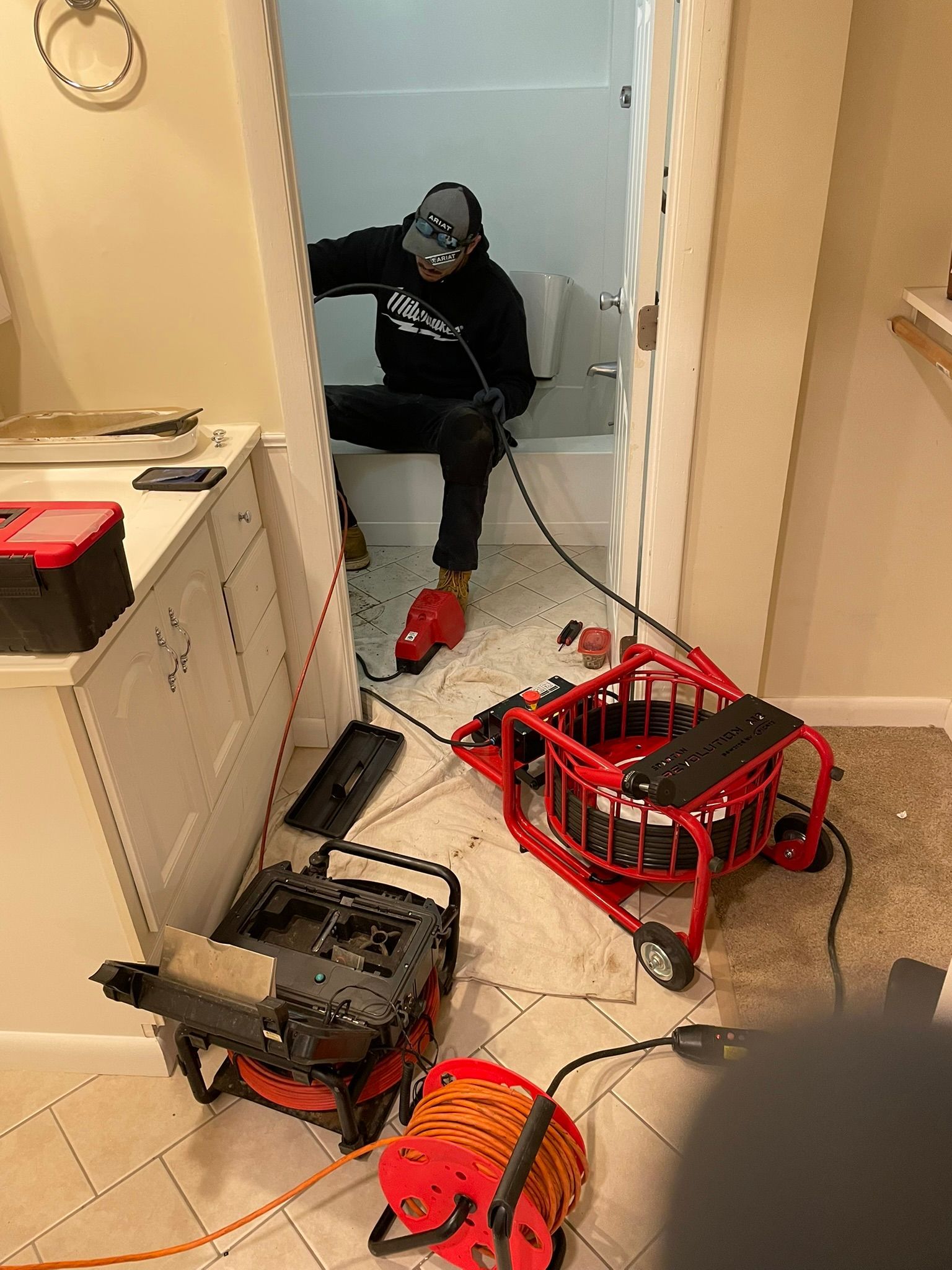 A man is sitting on a toilet in a bathroom.