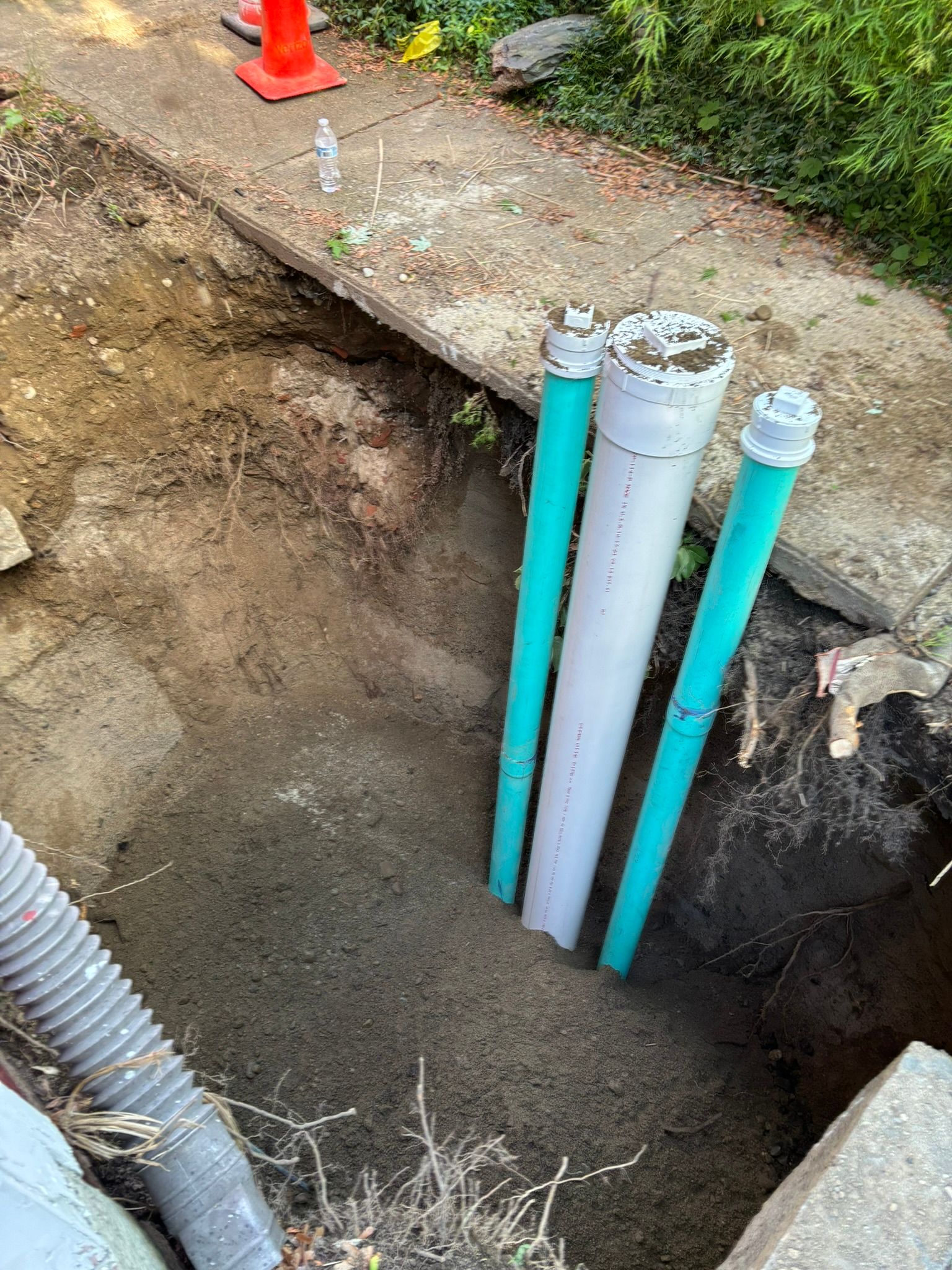 Three green and white pipes are sitting in a hole in the ground.