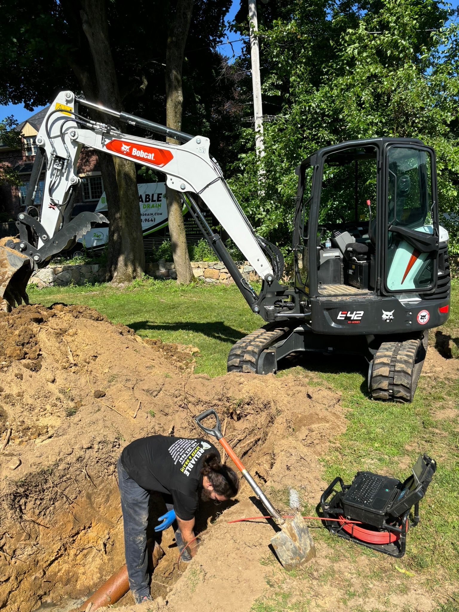 A man is digging in the dirt next to a small excavator.
