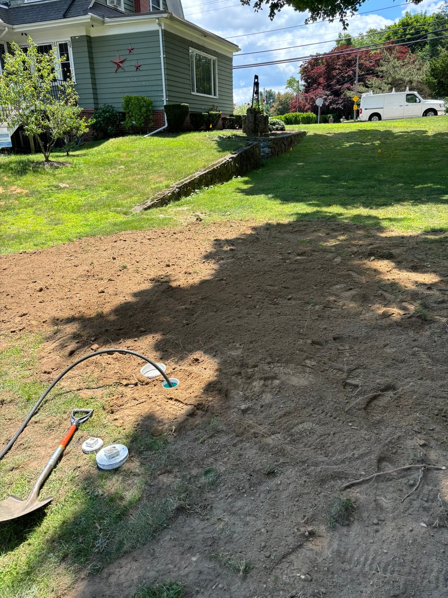 A shovel is sitting on top of a pile of dirt in front of a house.