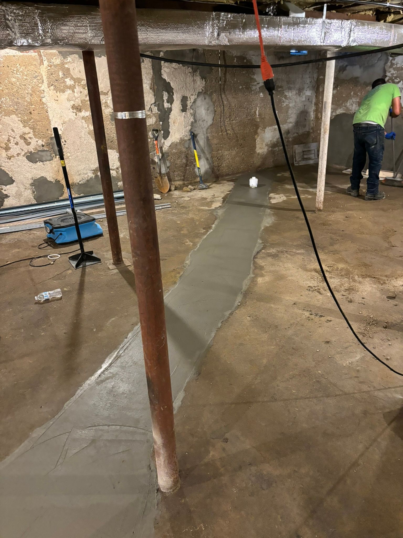 A man is working on a concrete floor in a basement.