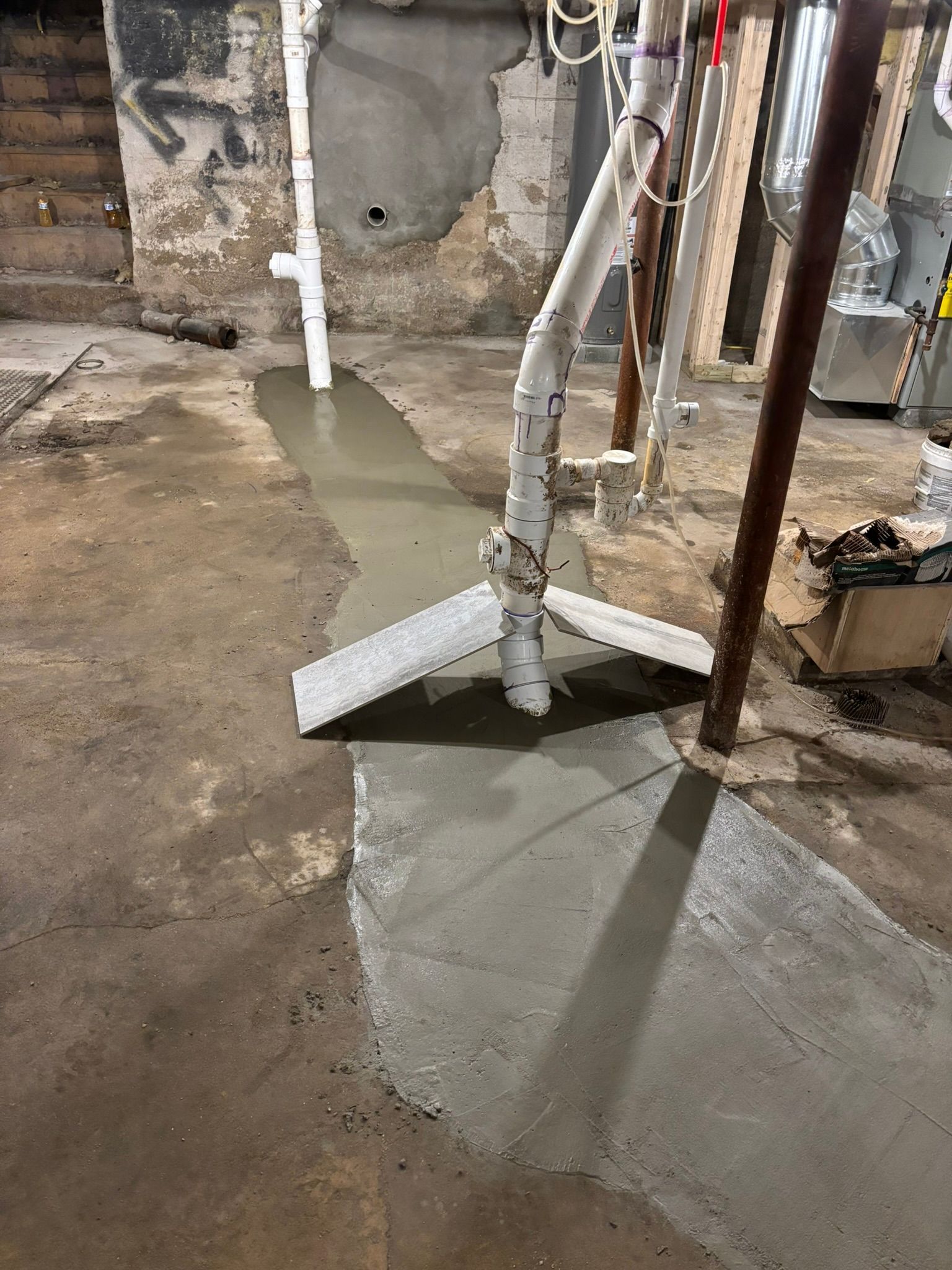 A concrete floor in a basement with a pipe in the middle of it.