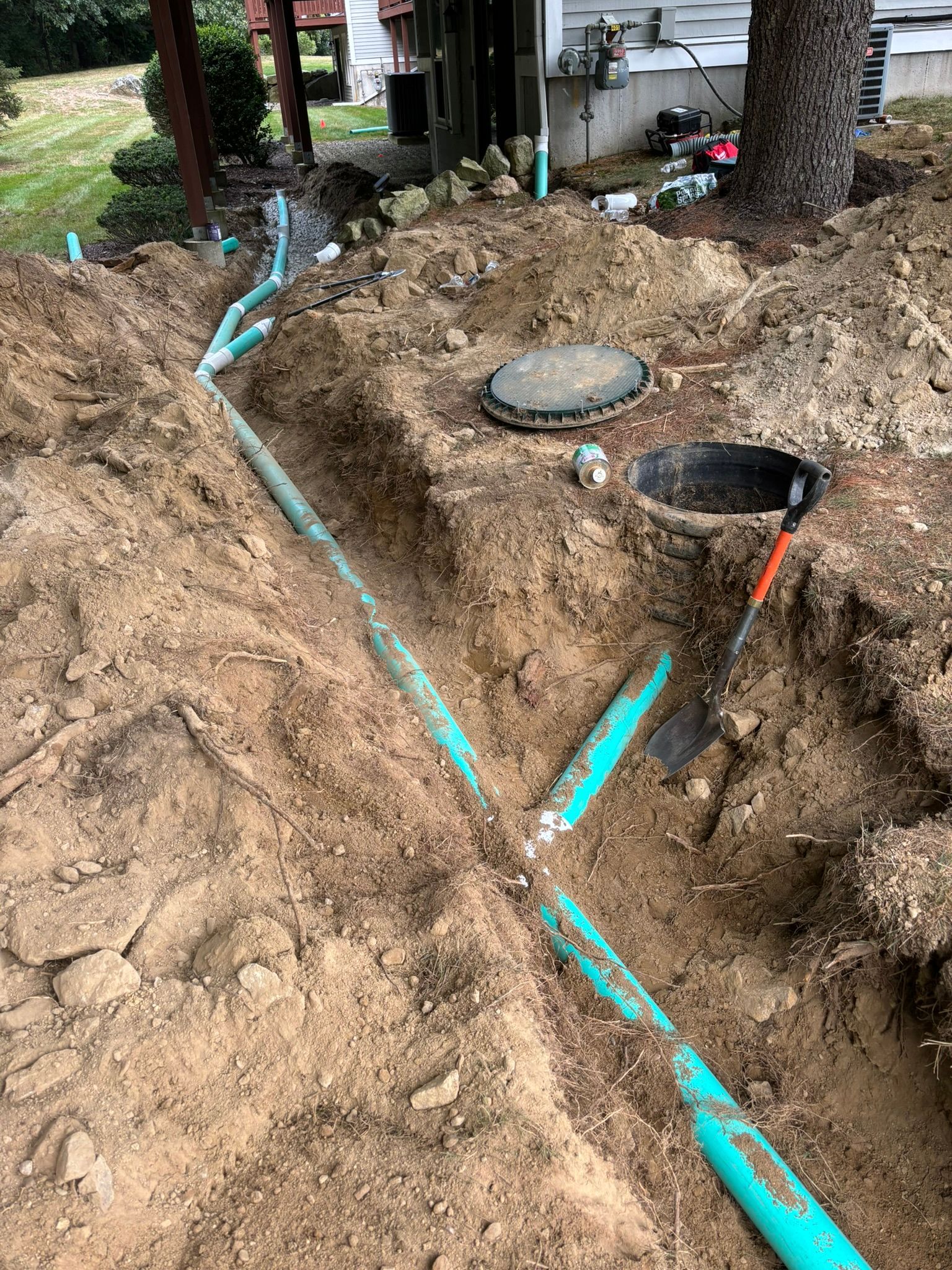 A drainage system is being installed in the dirt next to a house.