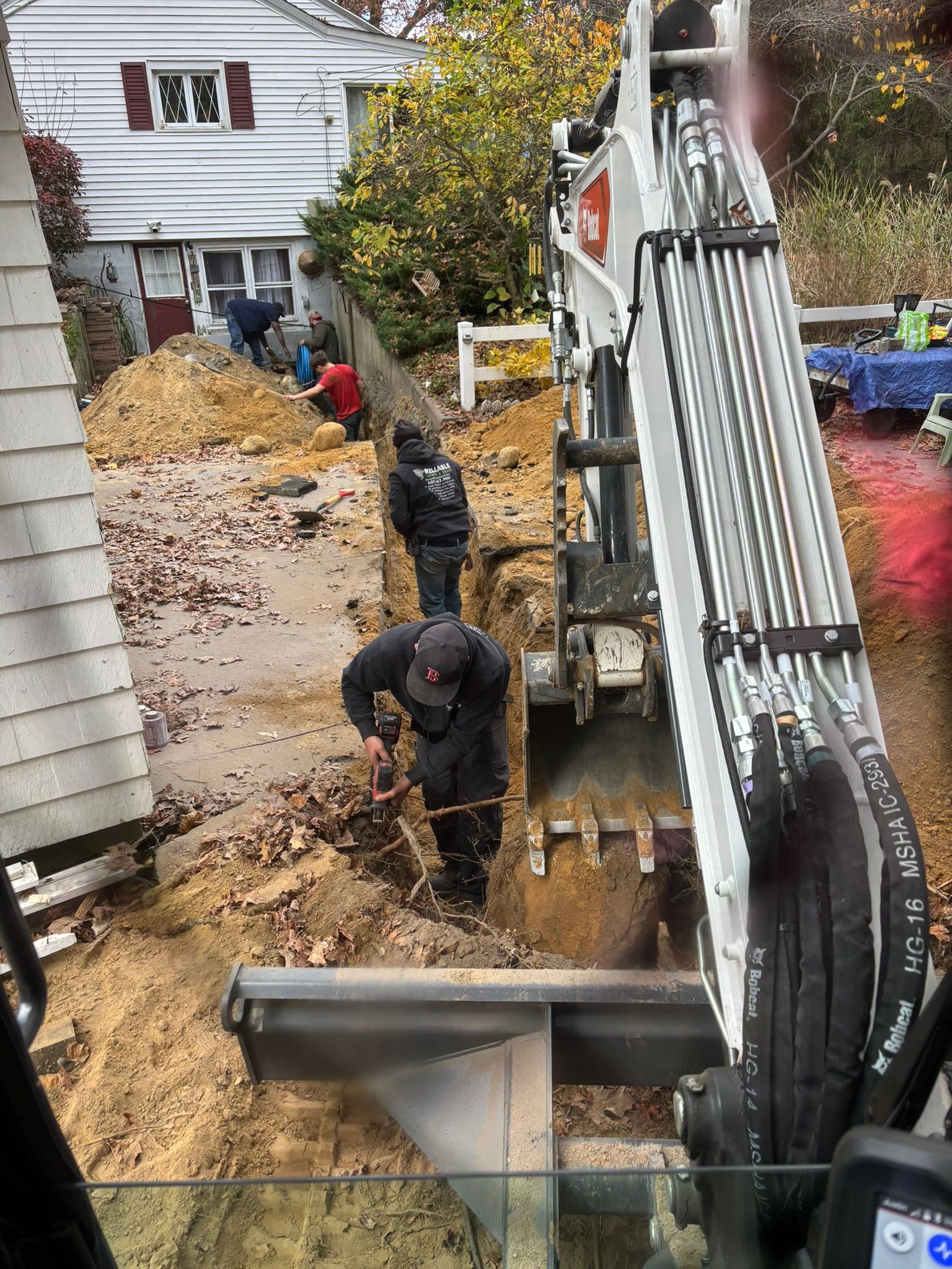 A group of men are digging a hole in the dirt in front of a house.