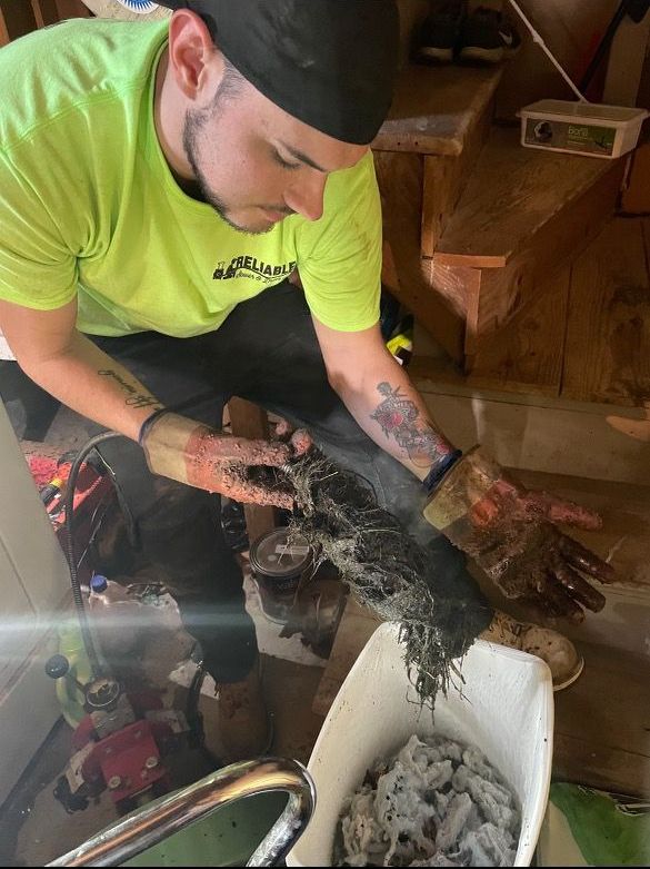 A man is cleaning a drain in a bathroom.
