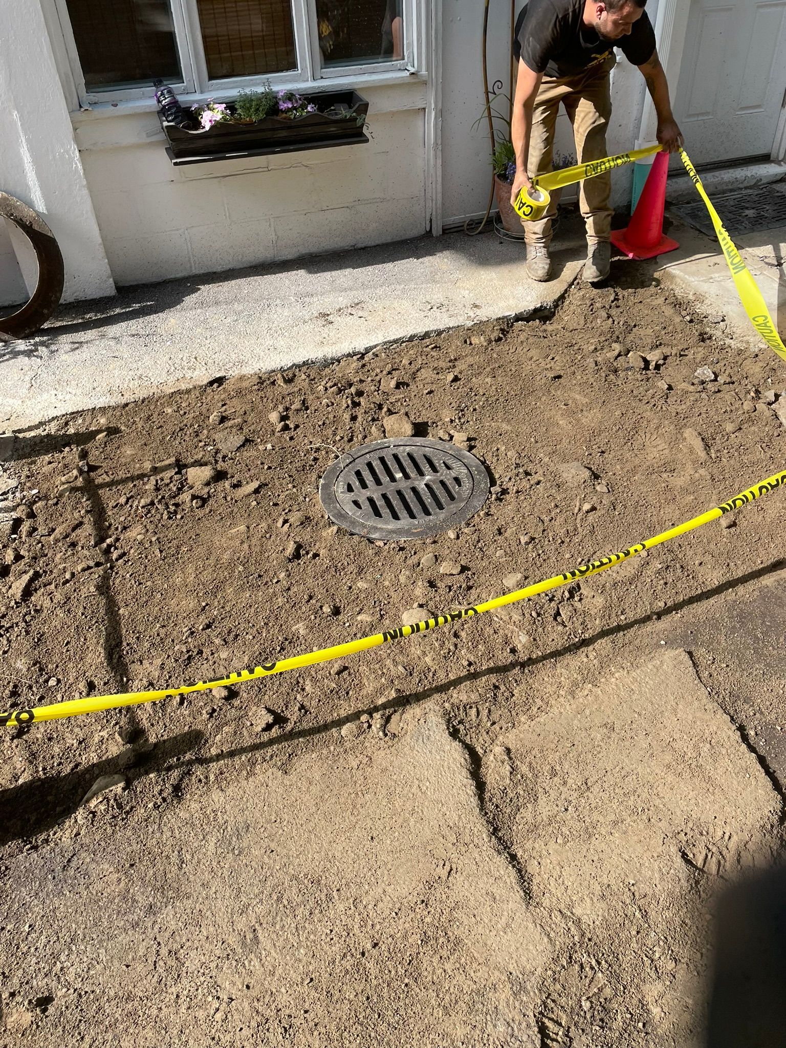 A man is standing in the dirt next to a manhole cover.