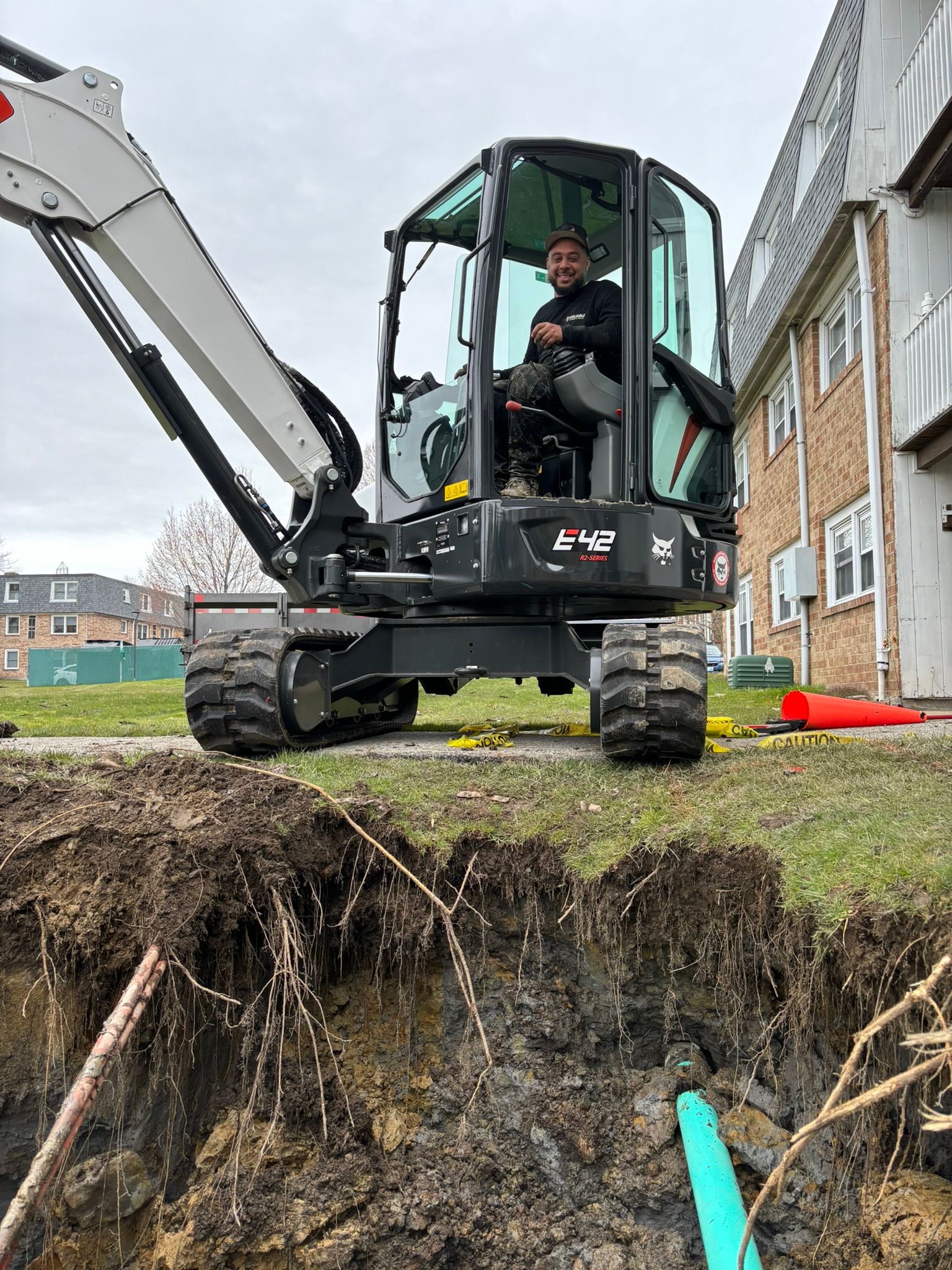 A man is driving a small excavator in a hole in the ground.