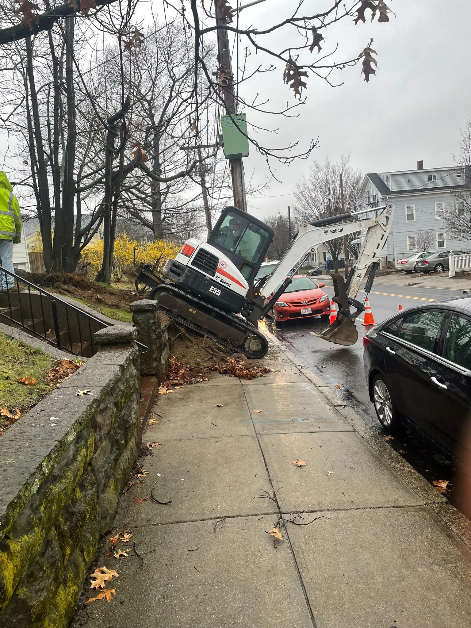 A bulldozer is sitting on the sidewalk next to a tree.