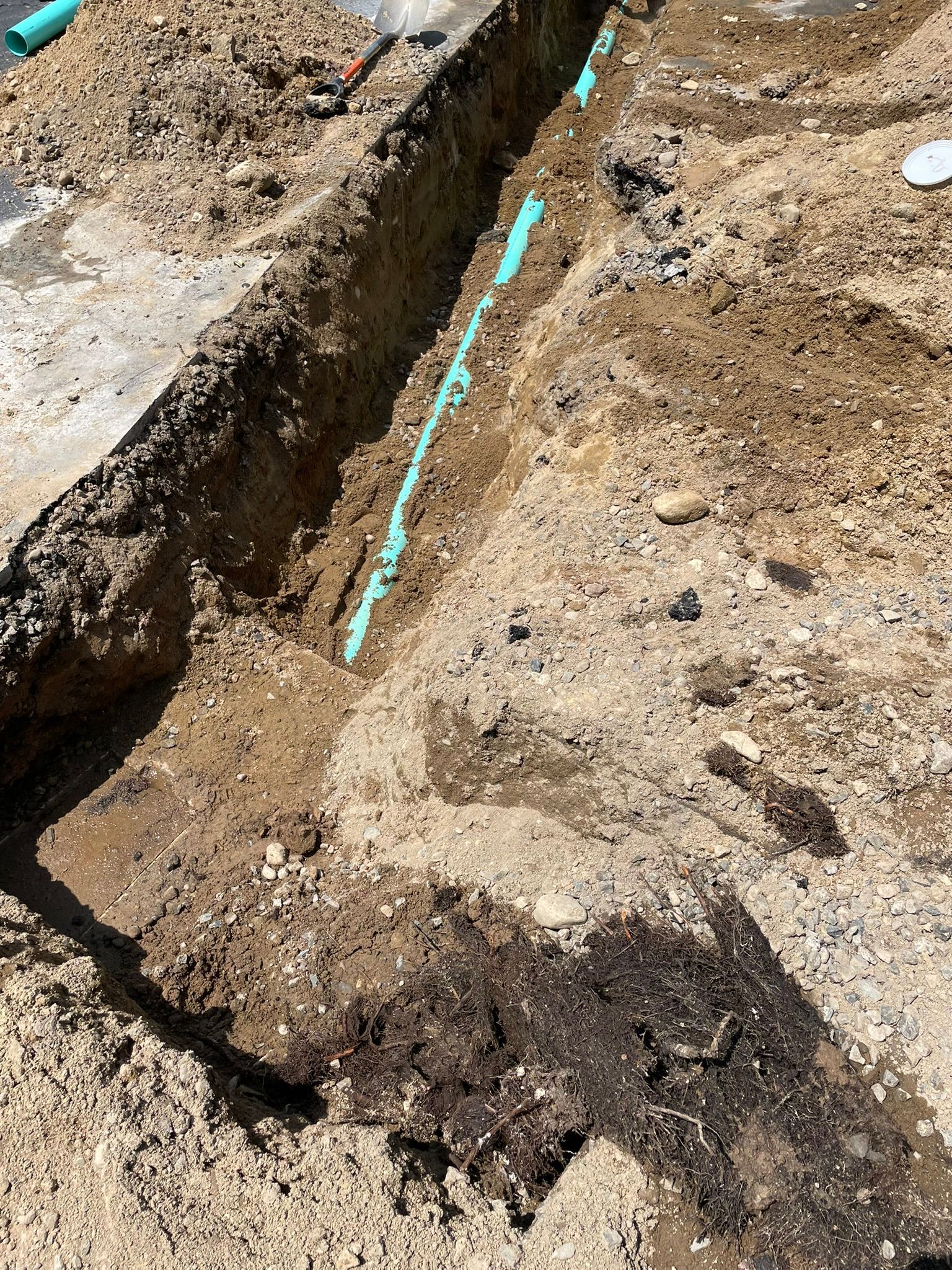 A drain pipe is being installed in a hole in the ground.