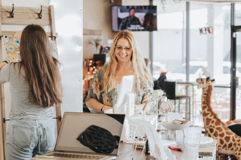 Two women are standing at a counter in a store.