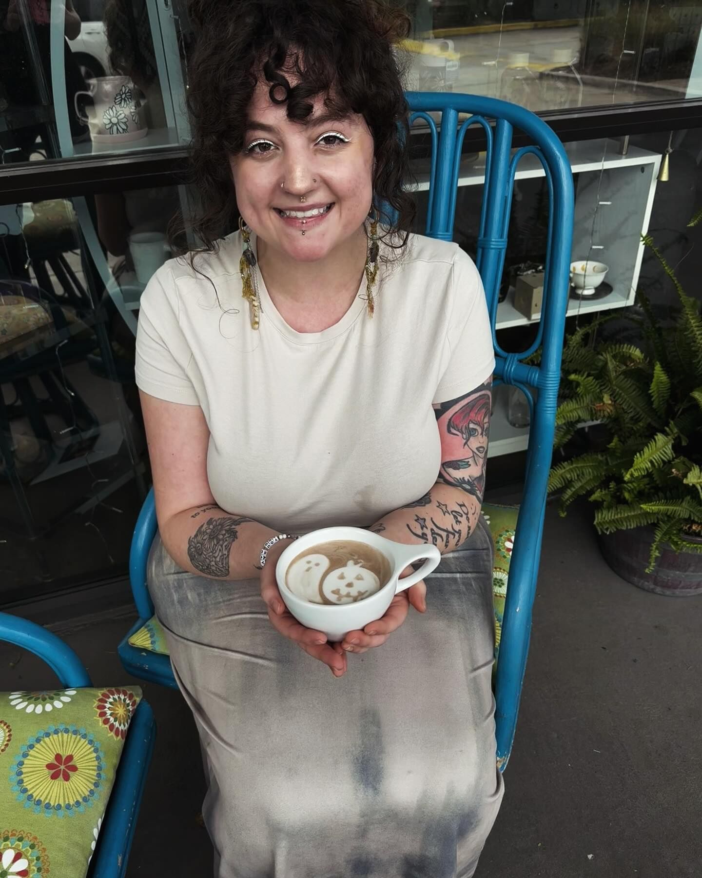 A woman is sitting in a chair holding a cup of coffee