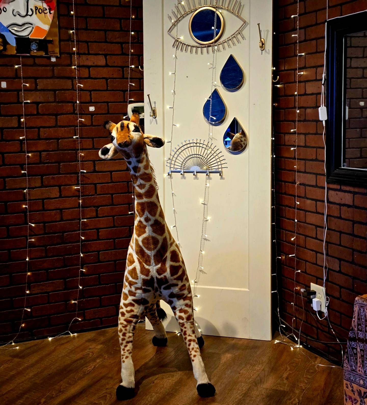 A stuffed giraffe is standing in front of a brick wall