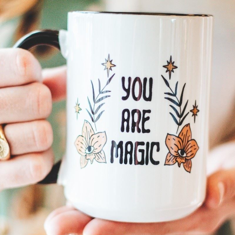 A person is holding a mug that says you are magic
