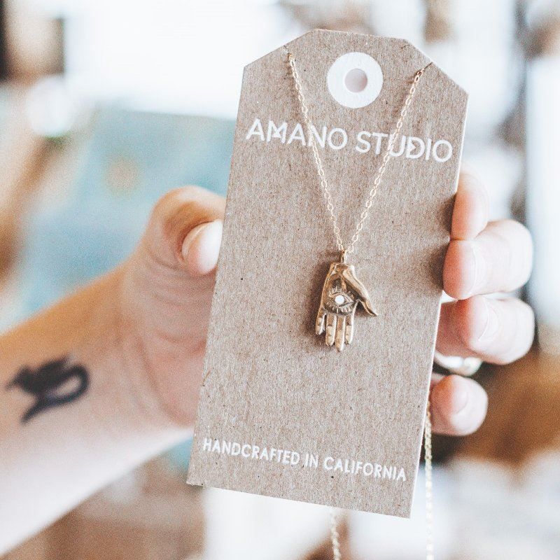A person is holding a card that says amano studio on it