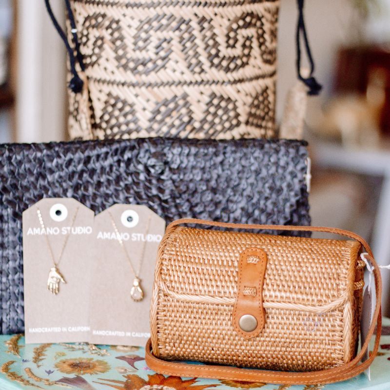 A wicker purse sits on a table next to a necklace and earrings