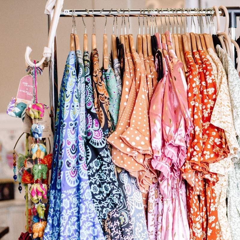 A rack of colorful clothes hanging on wooden hangers
