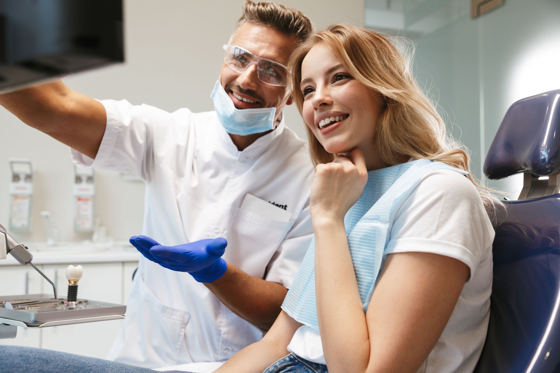 Dentist showing patient a dental X-ray. Both smiling, in a dental office.