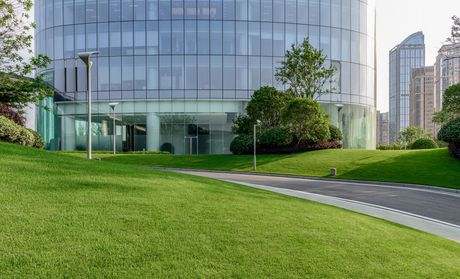 A large building with a lot of windows is surrounded by grass and trees.