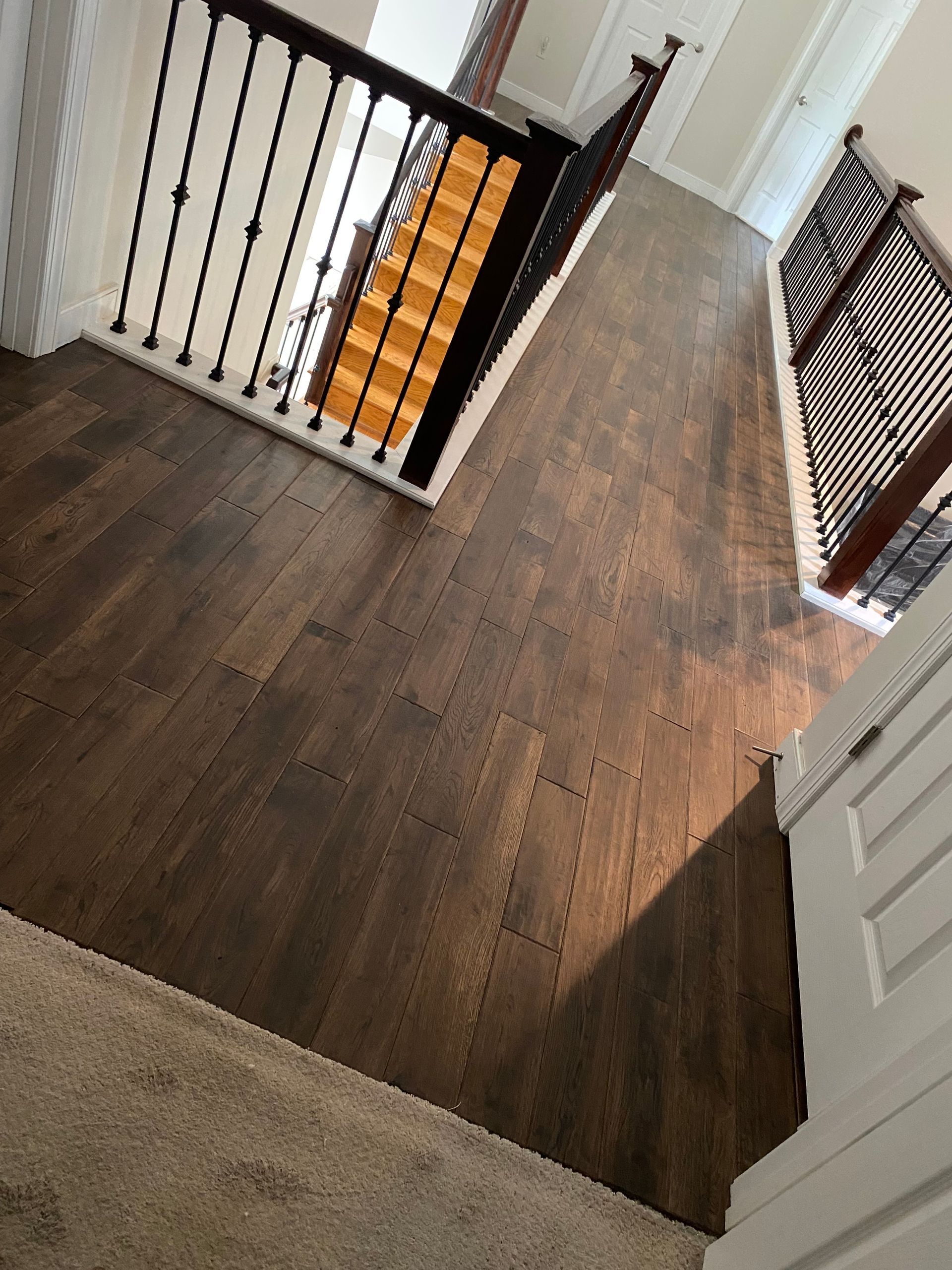Dark wood floors and staircase with black railing in a home's foyer.