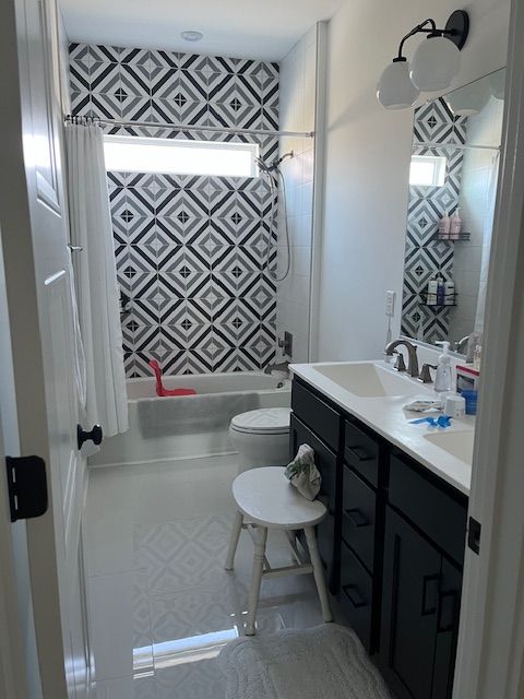 Bathroom with black vanity, geometric tile accent wall, and white fixtures.