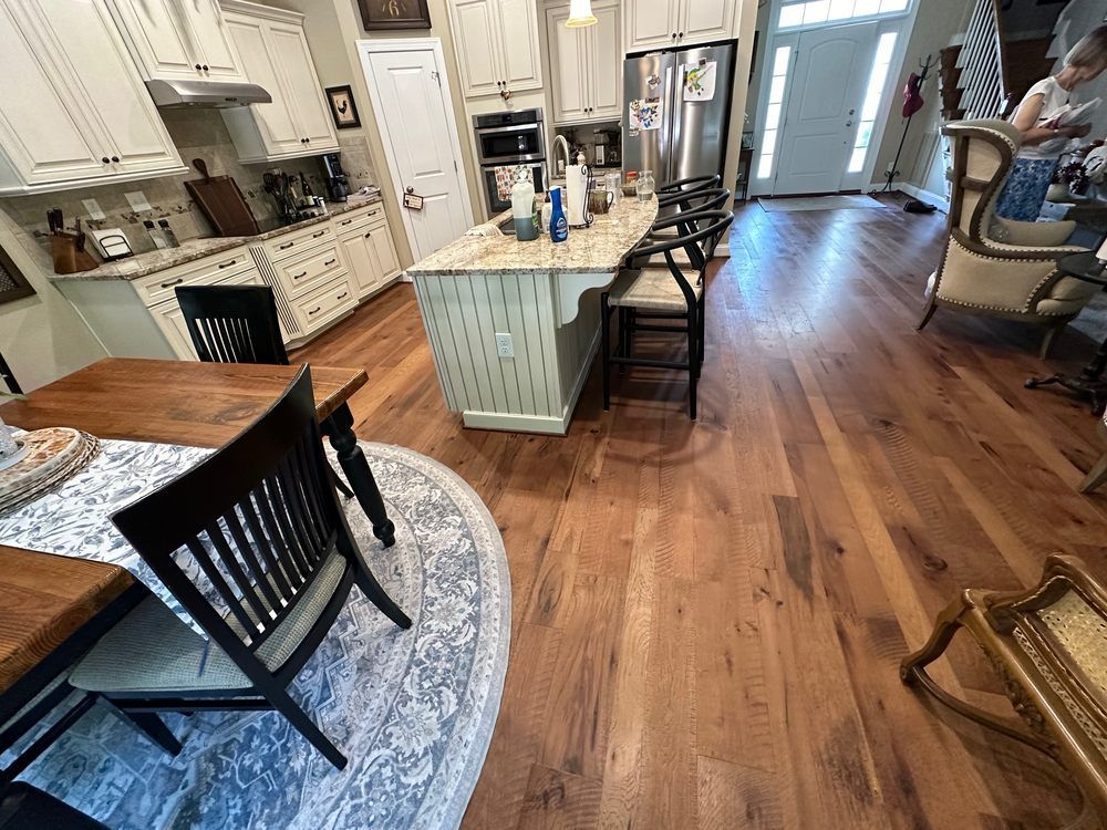 Hardwood floor in a kitchen with an island, table, chairs, and person in the background.