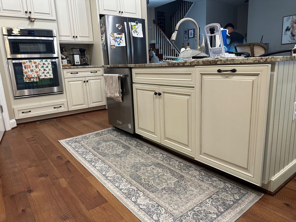 Kitchen with hardwood floors, cream cabinets, stainless steel appliances, and an area rug.