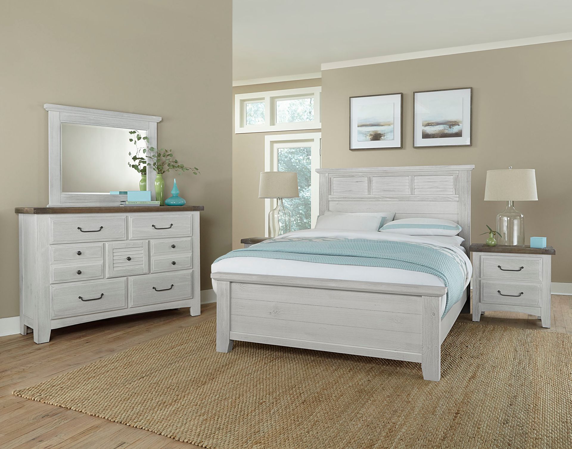 A bedroom with a bed , dresser , nightstand and mirror.