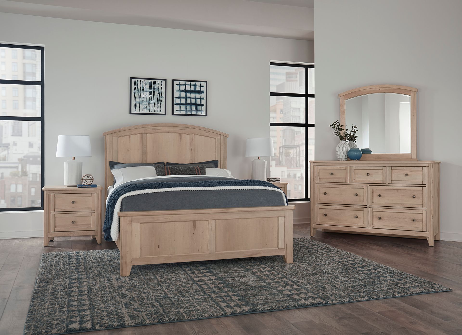 A bedroom with a bed , dresser , nightstand , mirror and rug.