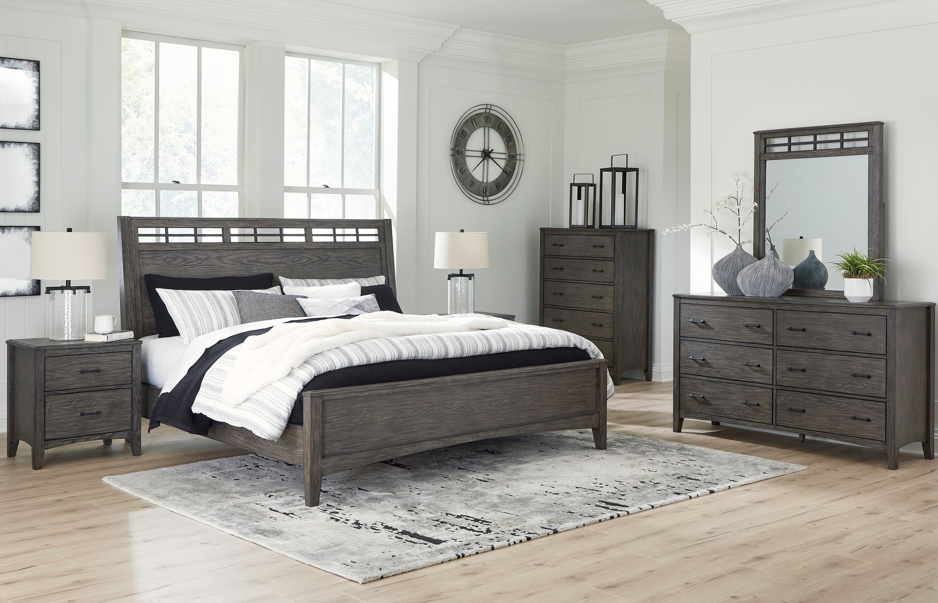 A bedroom with a bed , dresser , nightstand , mirror and rug.