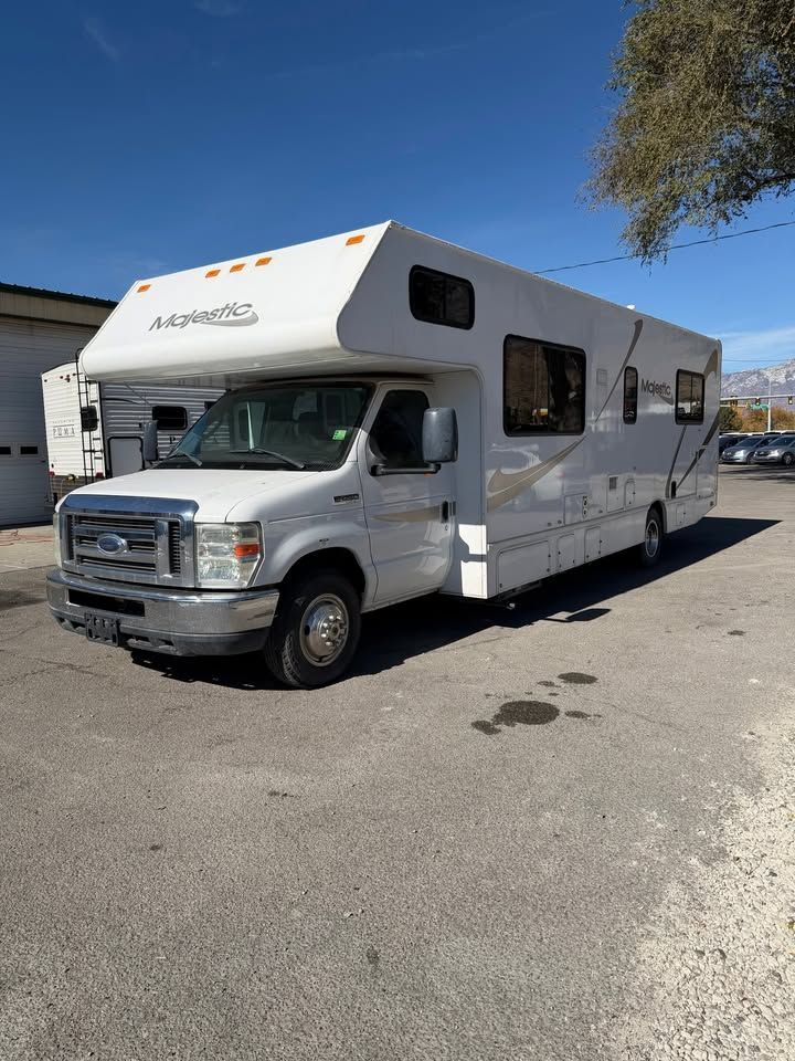 White motorized RV parked on pavement, bright sunny day.