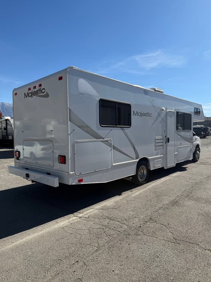 White Majestic RV parked on asphalt on a sunny day.