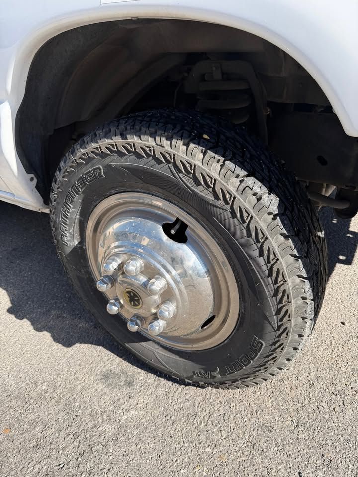 White truck tire with chrome hubcap on asphalt.