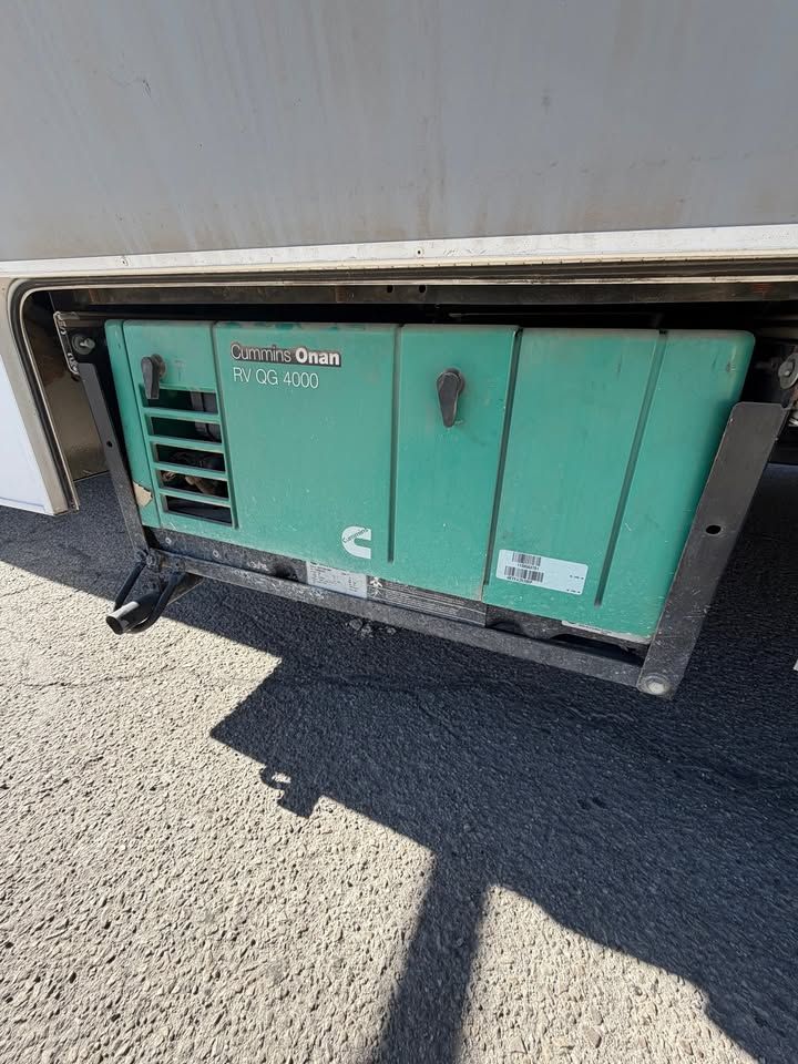 Green Onan generator, mounted on a motorhome, set outdoors.