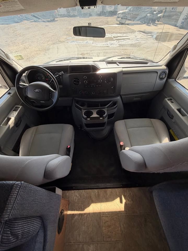 Interior view of a Ford van showing the driver and passenger seats, dashboard, and steering wheel.