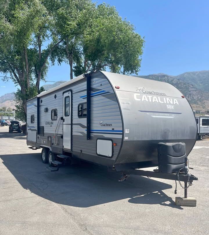 Gray Catalina travel trailer parked on pavement under a sunny sky.